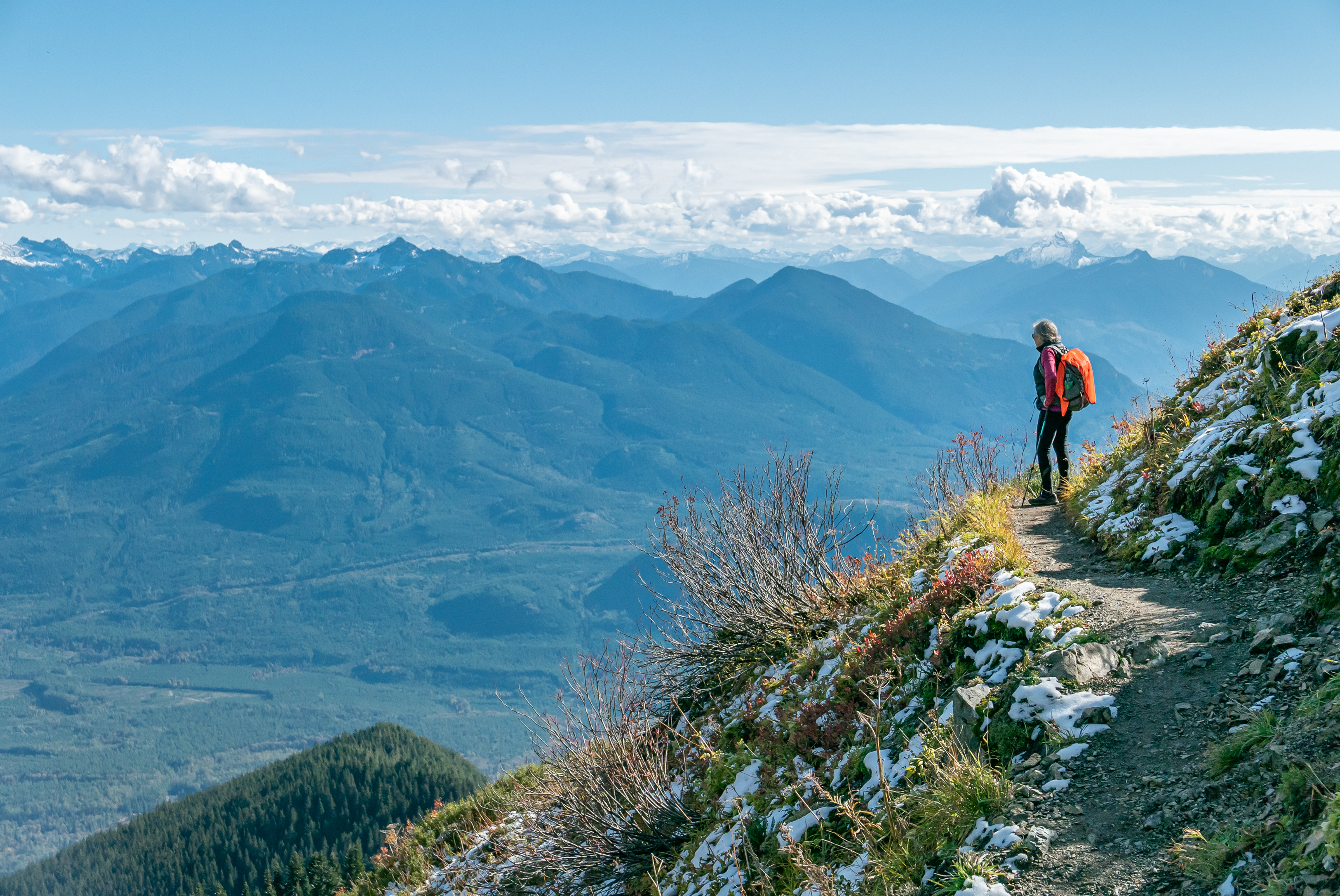 A photo of a hiker standing on a ridge that overlooks a valley.