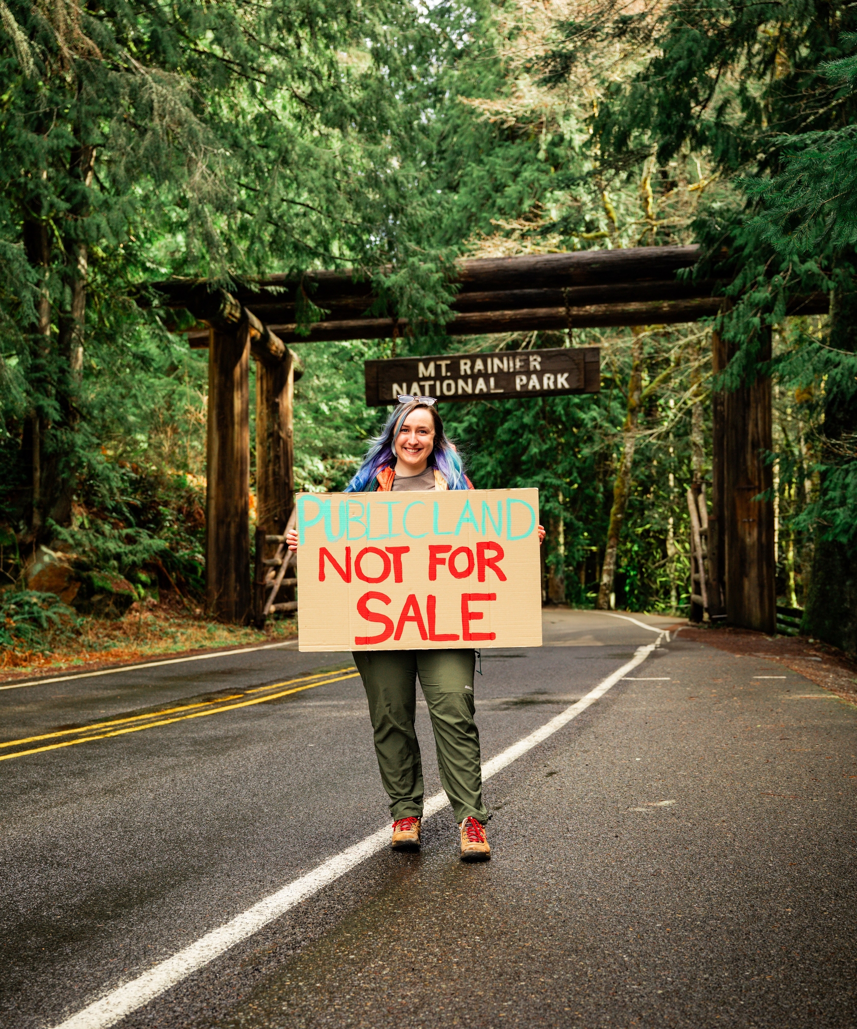 Advocate holds "Public lands are not for sale" sign outside Mount Rainier National Park. Photo by Chloe Medina