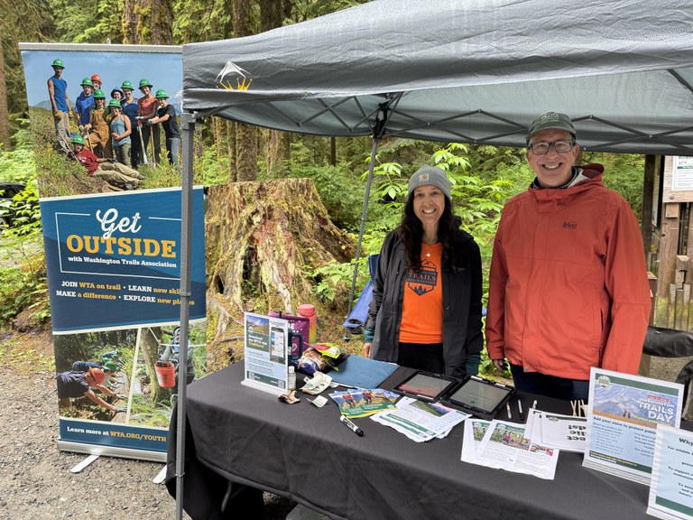 Ambassadors Table on WTD 2025 Two volunteers stand at a WTA outreach table, wearing WTA gear.