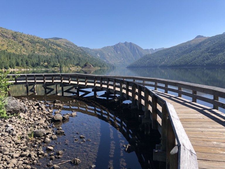 A wooden boardwalk curves out over a section of lake and returns to land on the other side. Photo by Jennekehikes 