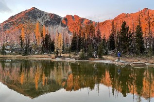 A photographer at an alpine lake in autumn.