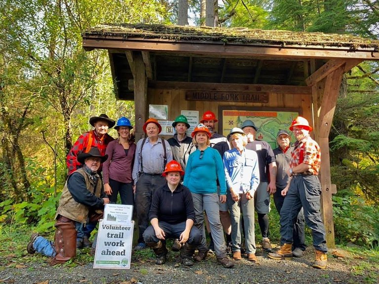 Trail work volunteers pose in front of the trailhead kiosk.