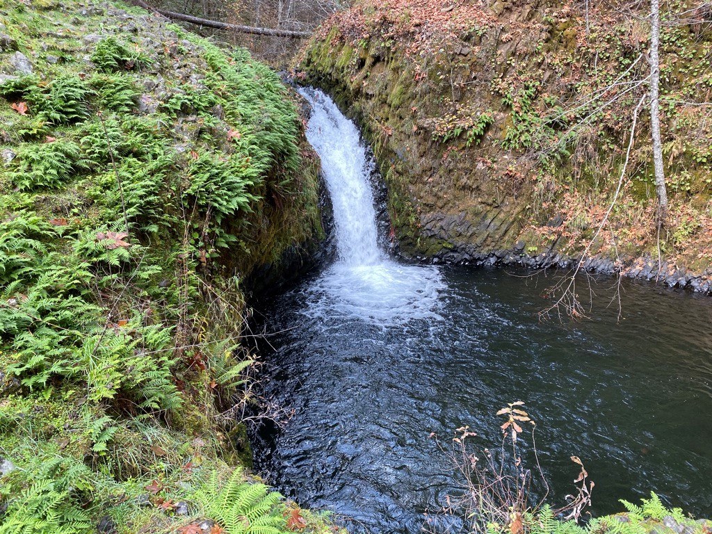 A waterfall glides down a slide of rocks into a calm pool below. Photo by Rod Hooker. 