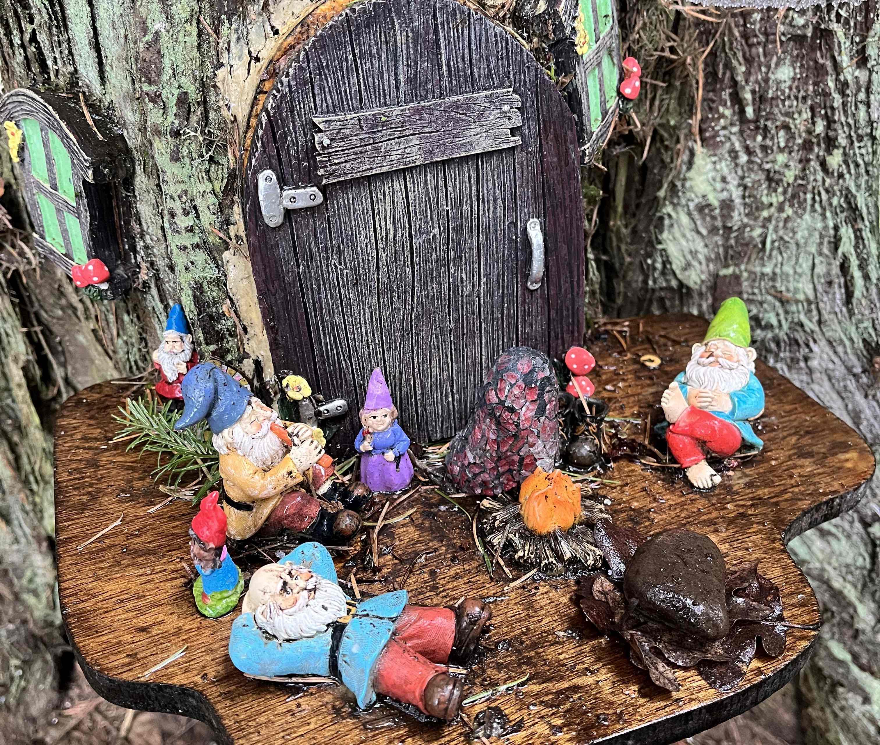 Small gnome village with colorful gnomes, a small door and window and mushroom decorations on the Burnt Bridge Creek trail. Photo by Mini_meanderer.