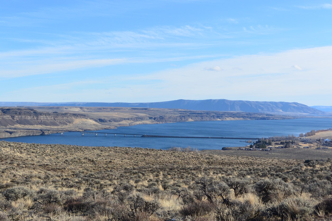 A view over a wide river cutting through shrub-steppe cliffs.