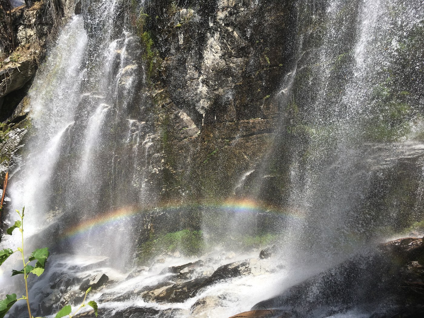 A small rainbow appears in the mist of a waterfall. Photo by DNielsen.