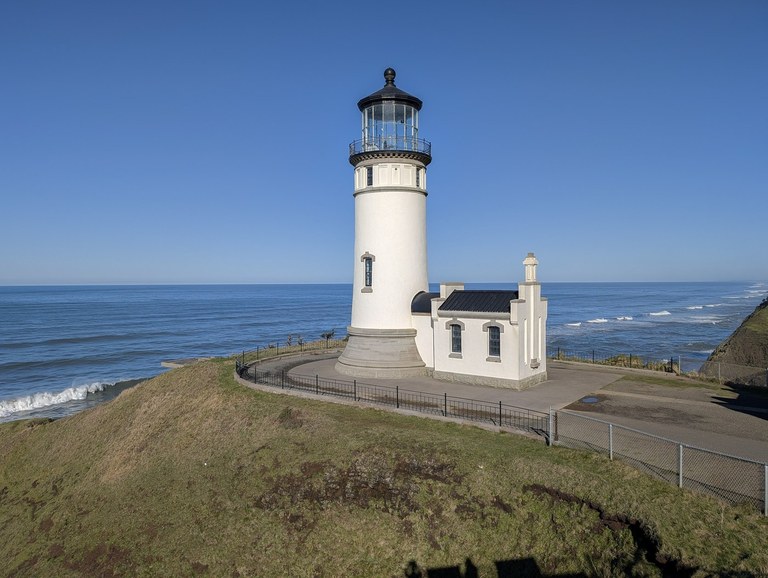 Lighthouses like this one have helped ships navigate the Clatsop Spit and rugged coast for years. Photo by trip reporter Ejain A lighthouse on a grass bluff overlooking the Pacific Ocean.