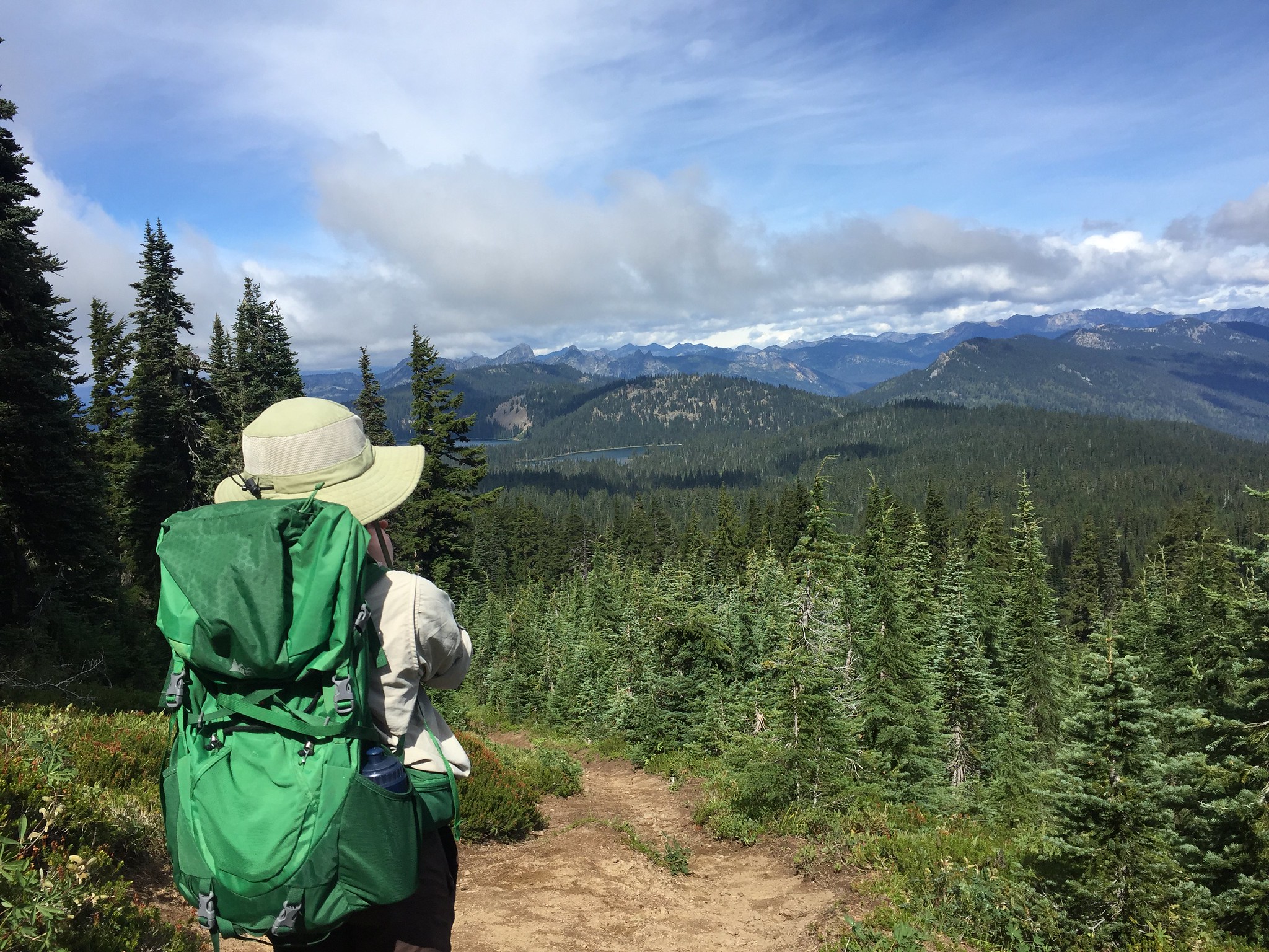 Hiker in foreground with mountains and lakes in distance