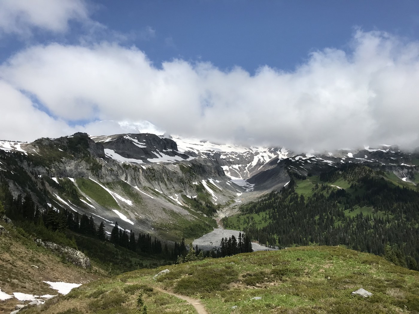 A long view down a gray rock valley that is still holding on to a few patches of snow.