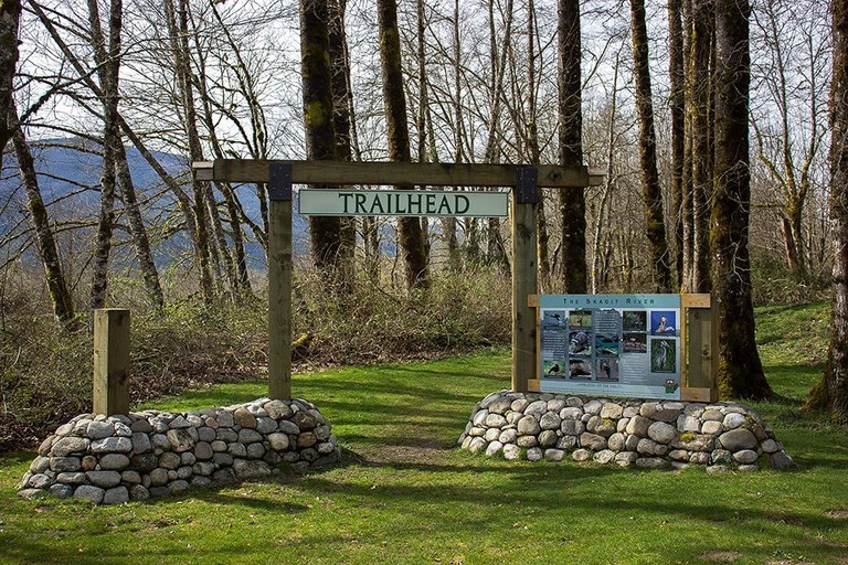 Interpretive trail signs line the entrance to a grassy trail.