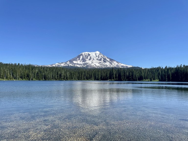 A distinct mountain towers over a blue lake. Photo by rupas.