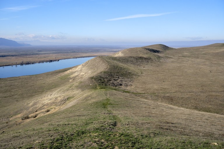 A gentle grassy ridge extends into the distance where the Columbia River flows.