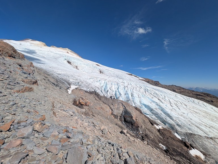 A glacier with blue and white coloring on the side of a mountain.