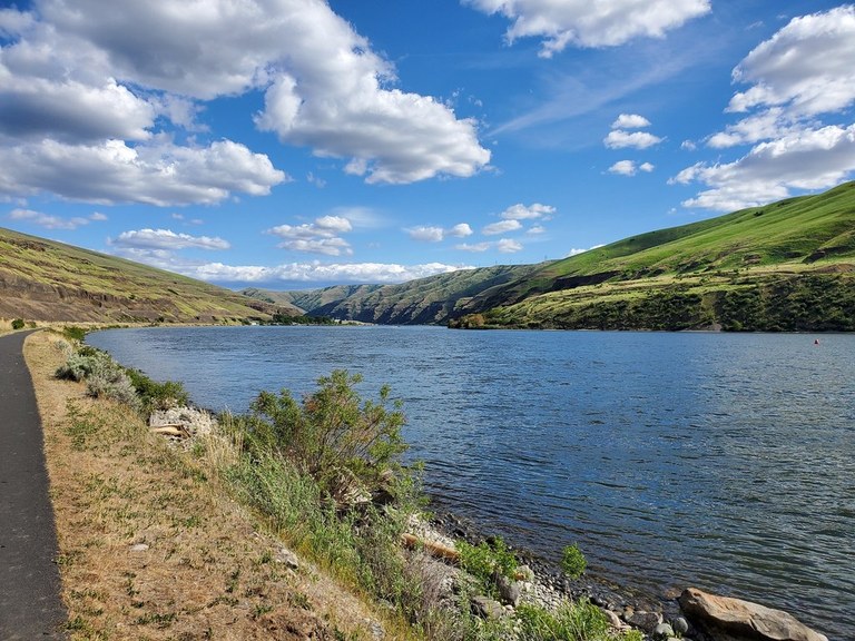 Bird, jog or amble along an iconic PNW waterway. Photo by Aaron Czechkowski A paved trail hugs the rocky shoreline of a wide river.