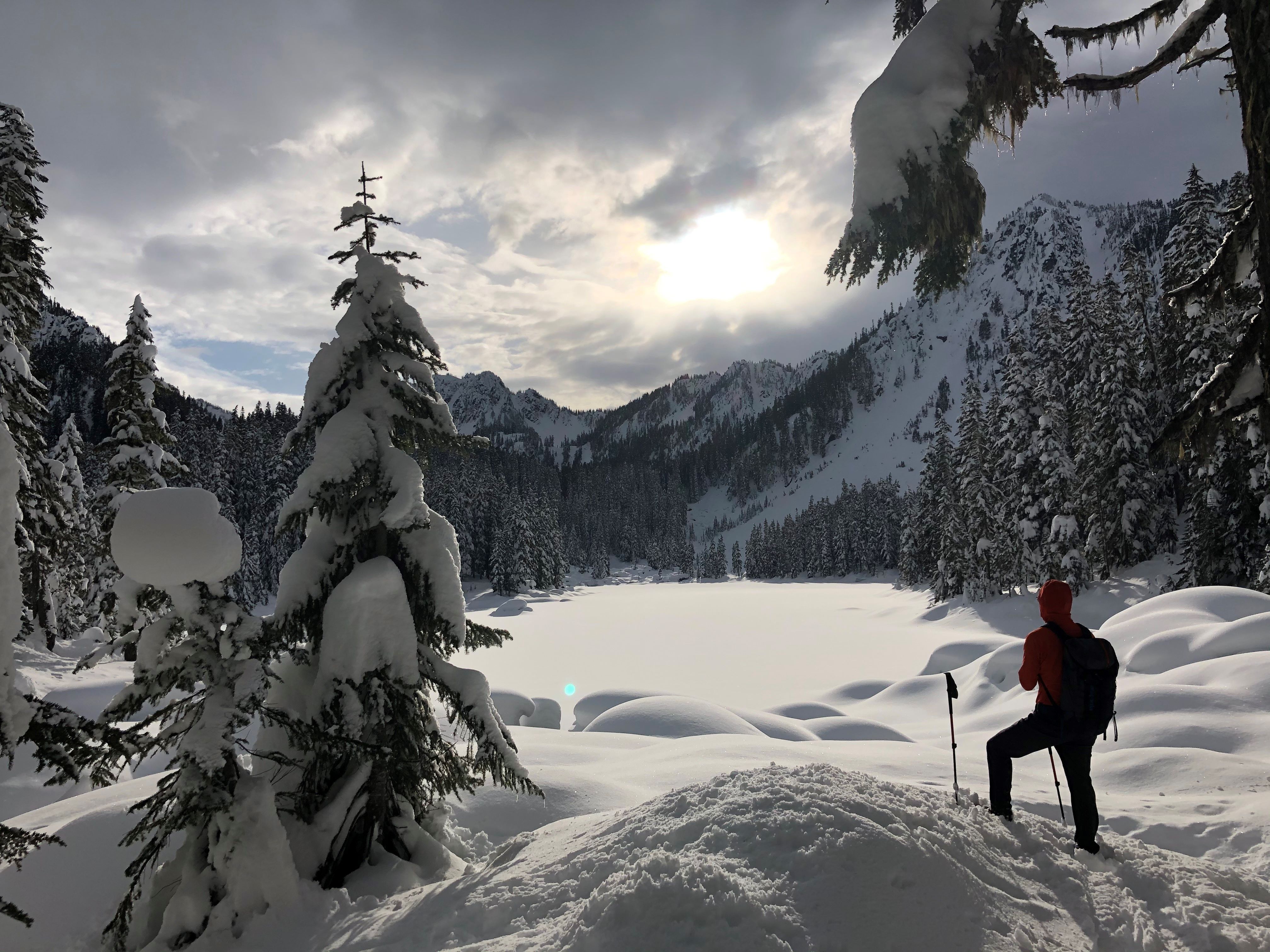 A snowshoer stands at Surprise Lake in the snow. Photo by twochewy.
