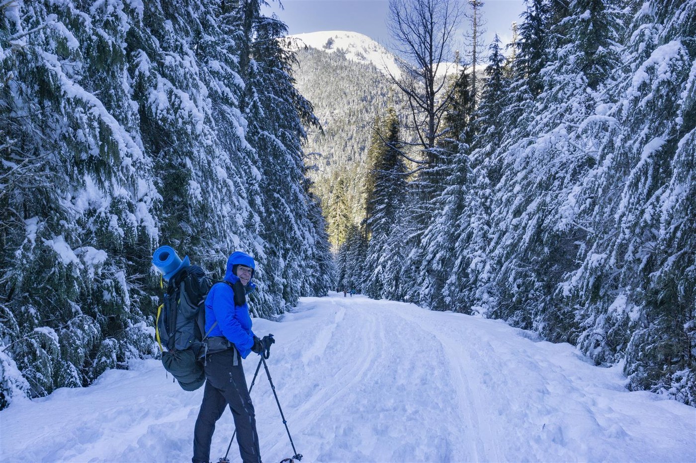 White Salmon Road Snowshoe. geezerhiker. A man stands on a snowy road with a big backpack.