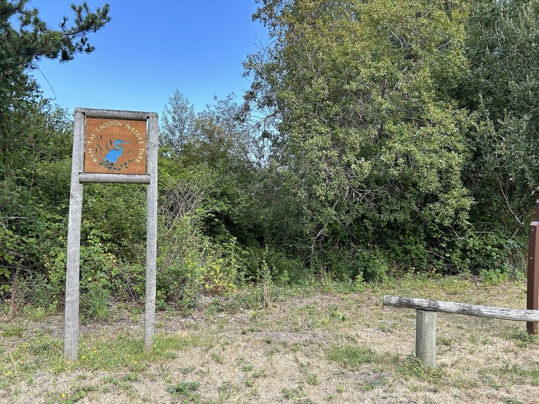 A large wooden sign in a field against a blue sky. 