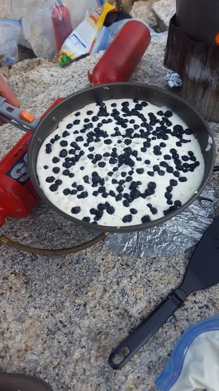 A pancake is cooked over a gas stove in the backcountry.