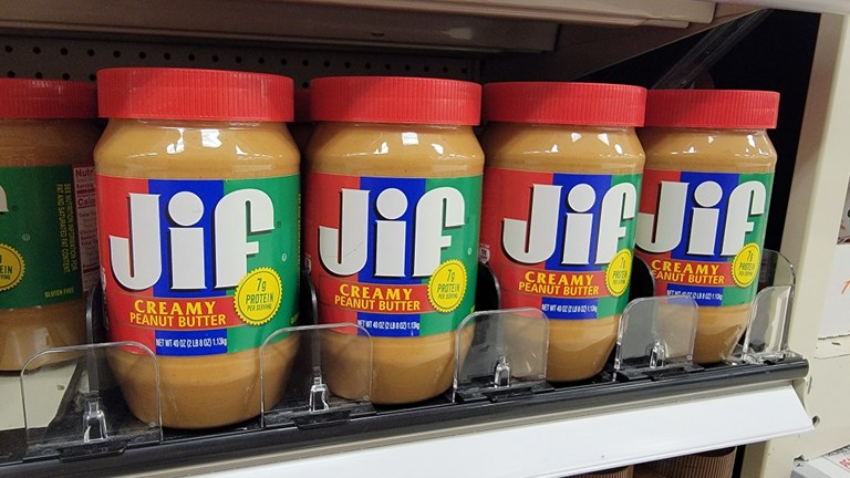 A row of peanut butter on a grocery store shelf.
