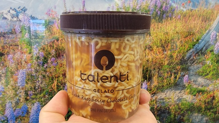 A jar of ramen sits in front of a landscape photo.