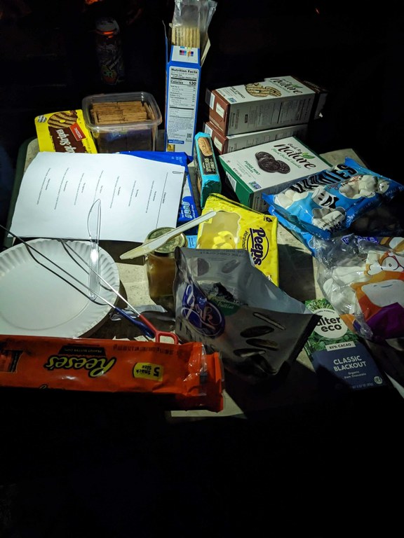 A table of s'mores buffet items, including various crackers, marshmallows, and chocolate at nighttime. Photo by Tiffany Chou.