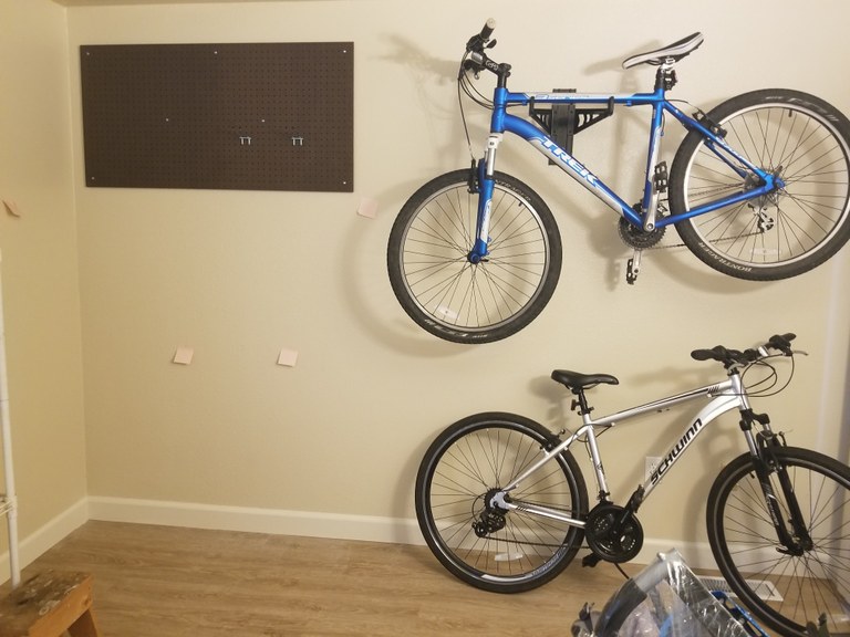 One bike is suspended on a wall with a rack. The other sites below it with a kickstand.