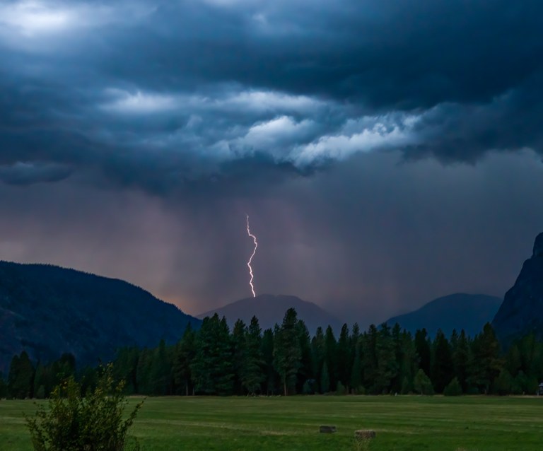 A lightning bolt strikes a distant mountain range.