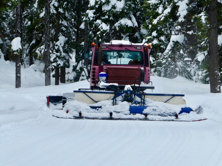 Grooming machine on a snowy trail. 