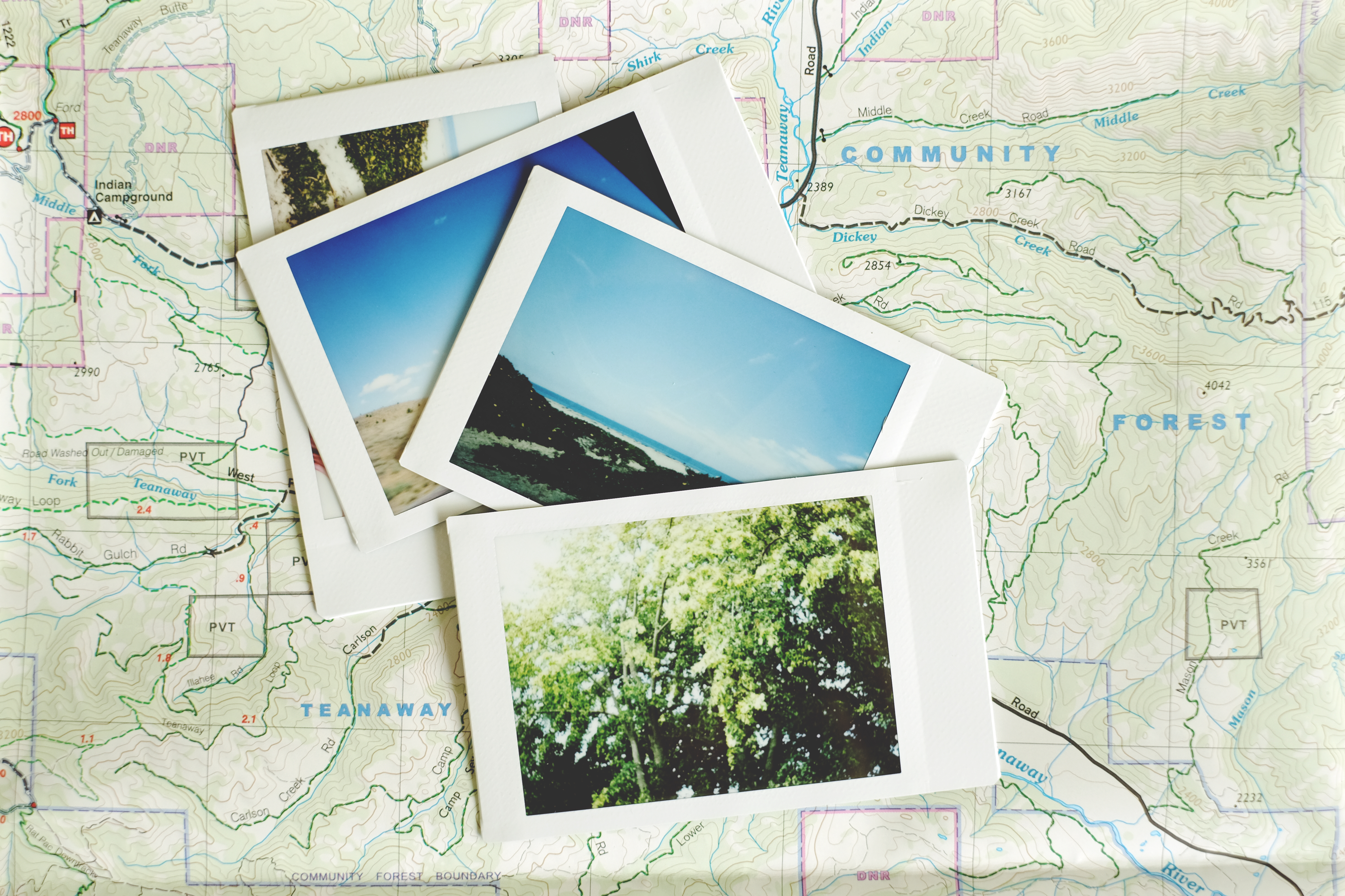 A stack of instant photos sitting on a trail map A stack of instant photos sitting on a trail map