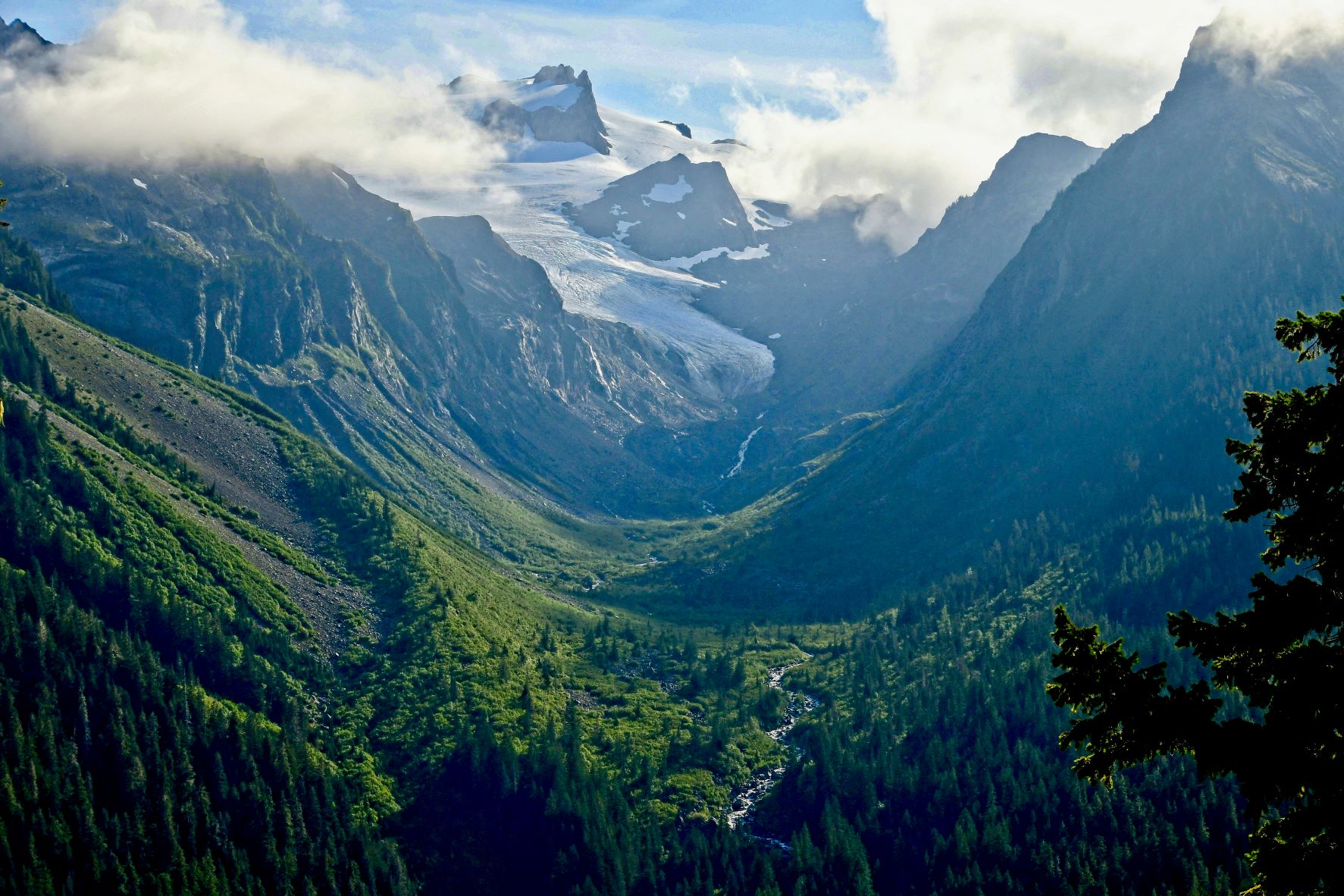 A view down a lush river valley with a mountain rising out from the end.