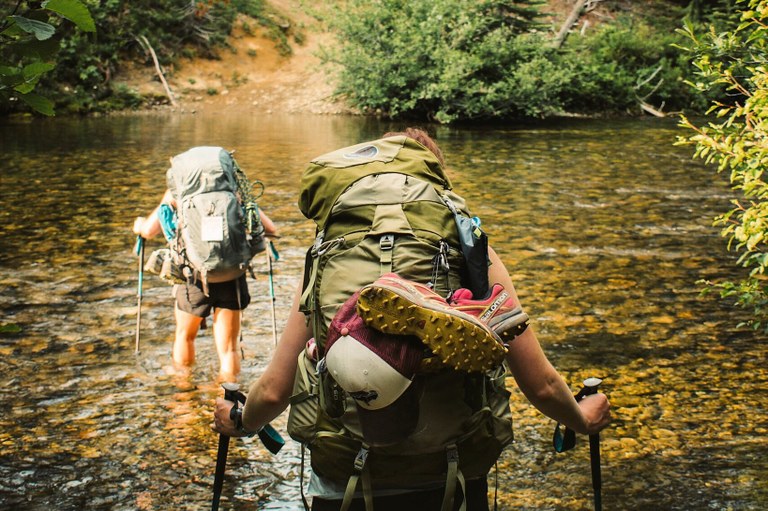 Hikers trek across a river.