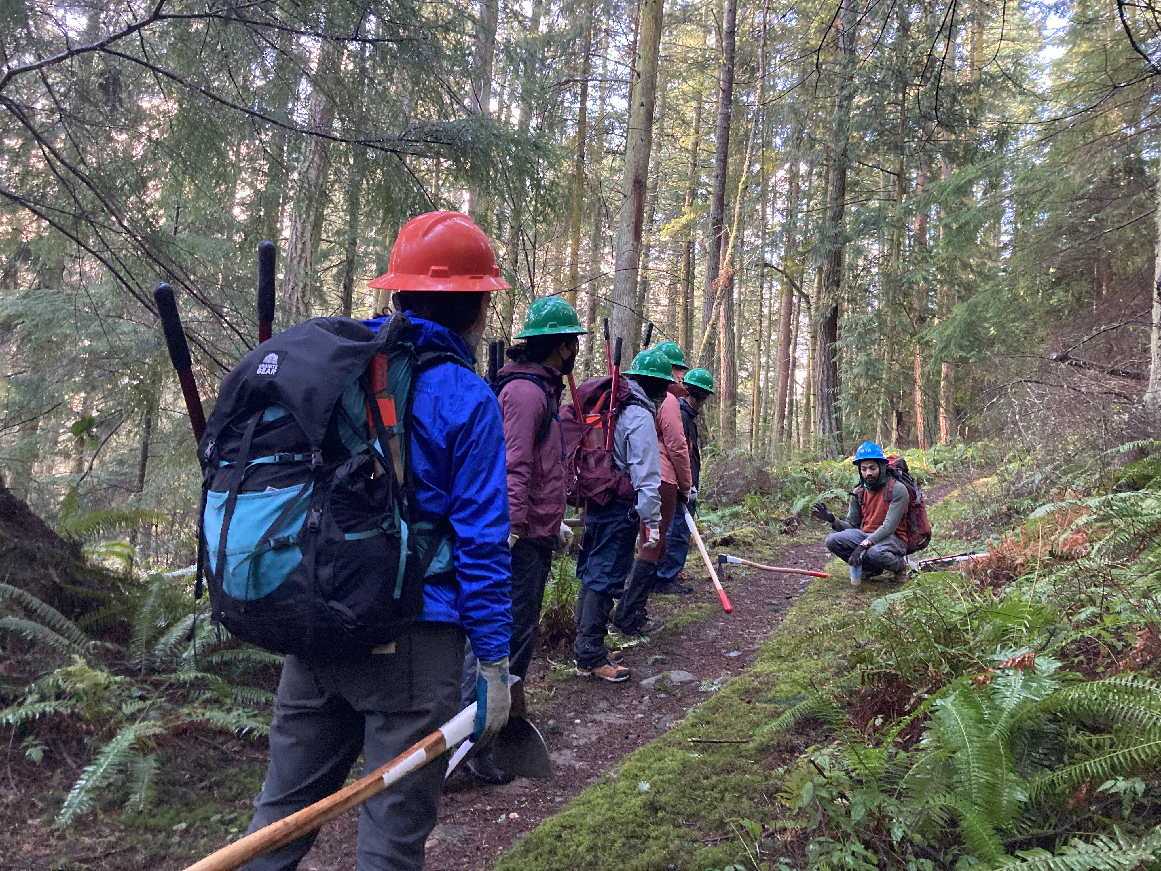 Emerging Leaders cohort carry tools up a trail to do trail maintenance.