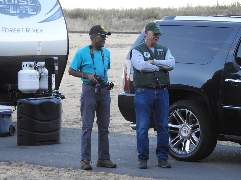 Host at Fort Worden Two folks stand at the end of a trailer, one with a Washington State Parks vest on, the other holding a camera around their neck.