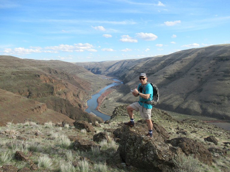 Craig Romano researching Columbia River Gorge book in Oregon's Cottonwood Canyon State Park. Photo by Craig Romano. Craig Romano researches the Columbia River Gorge from a rocky outcrop. The Columbia winds below in an eroded canyon.