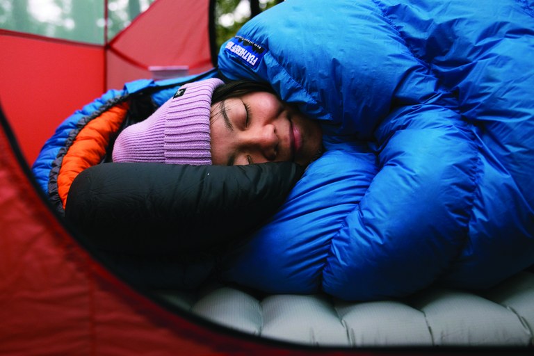 A hiker sleeps in a sleeping bag.