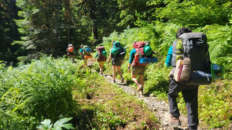 A string of WTA trail workers hike through beautiful wilderness, one of the many benefits of joining a work party.