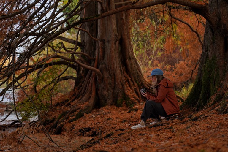 A hiker sits in a quiet spot, look at the back of digital camera.