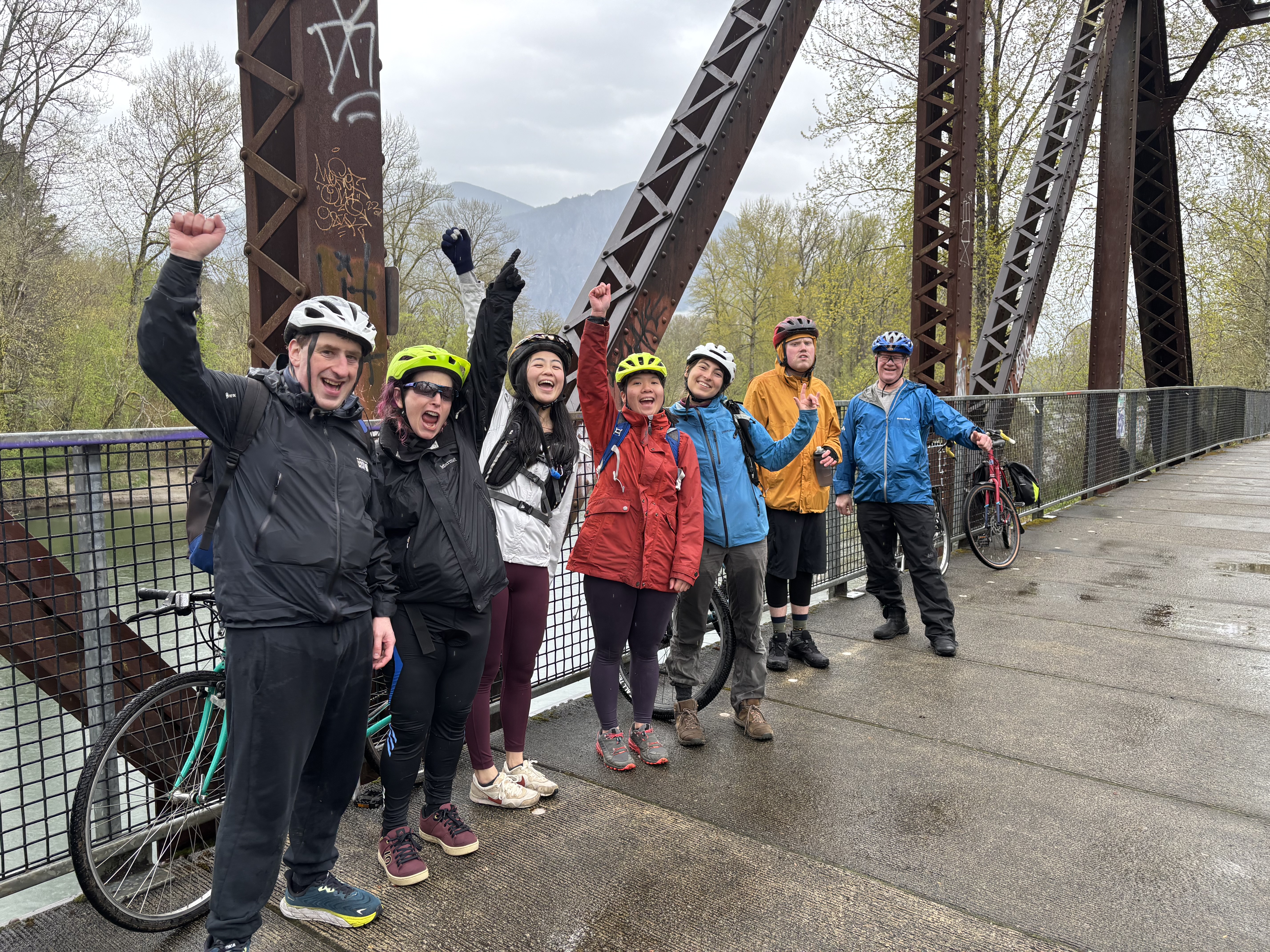 Smiling group on bridge with helmets and bikes.