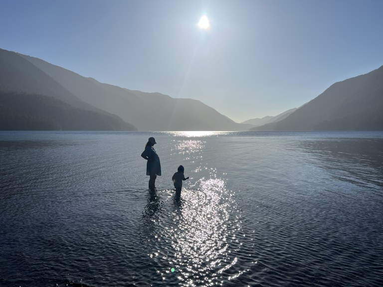 Lake Crescent. Photo by Sandy Johng A pregnant adult standing in a lake with a young child.