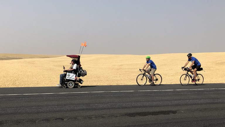 Ian took a nearly 500-mile ride across Washington, east to west, in 2018. Photo courtesy Ian Mackay Ian rides down a road with two cyclists behind him.