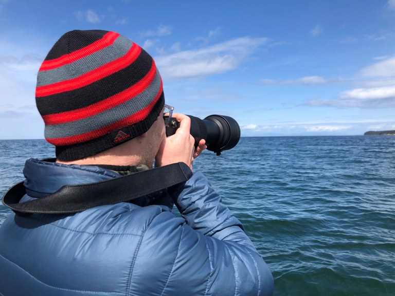 Matt with camera. Photo by Matt Leaman. Matt taking photos of orcas on the Salish Sea. Photo by Matt Leaman.