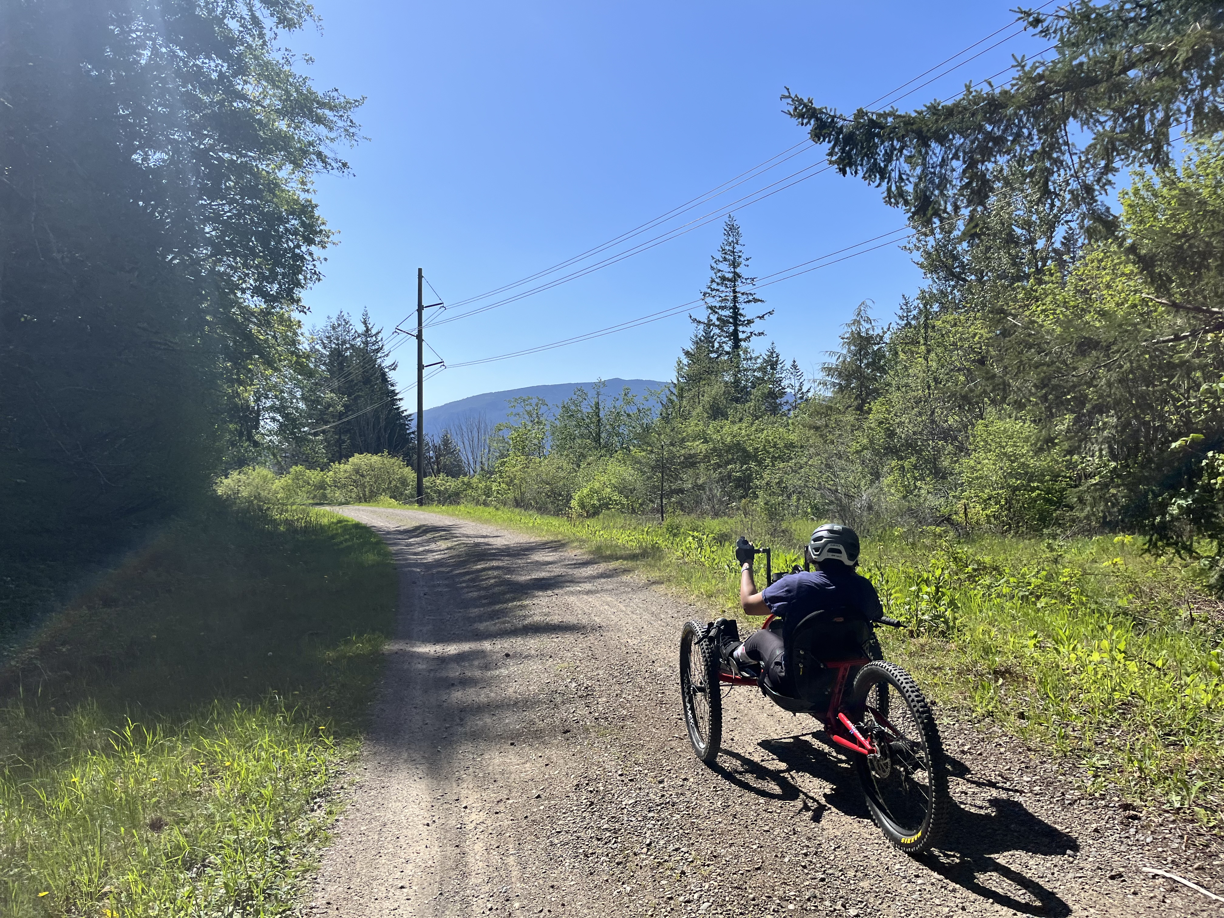 Person on adaptable bike on paved trail on sunny day.