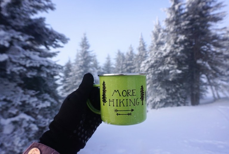 A mug in the snow that says "More Hiking"