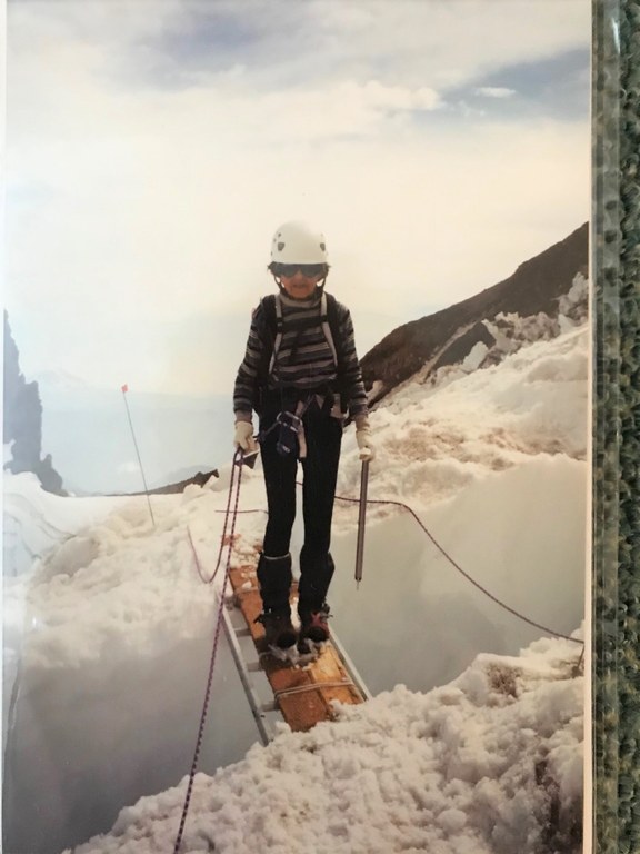 Bronka summiting Rainier at age 77. Bronka, in her climbing gear, stand on a snow bridge while climbing Mount Rainier.