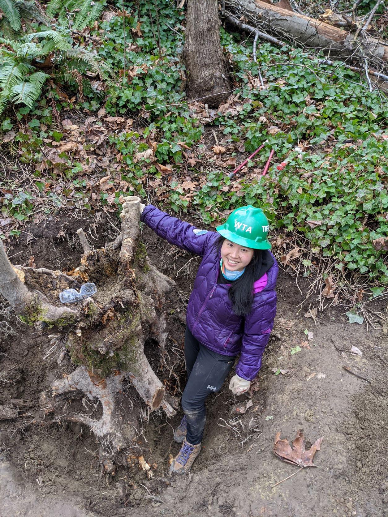 Tiffany posing next to a large tree trunk she's attempted to dig out of the trail at Dead Man's Pond in Puyallup. Photo by Zachary Toliver.