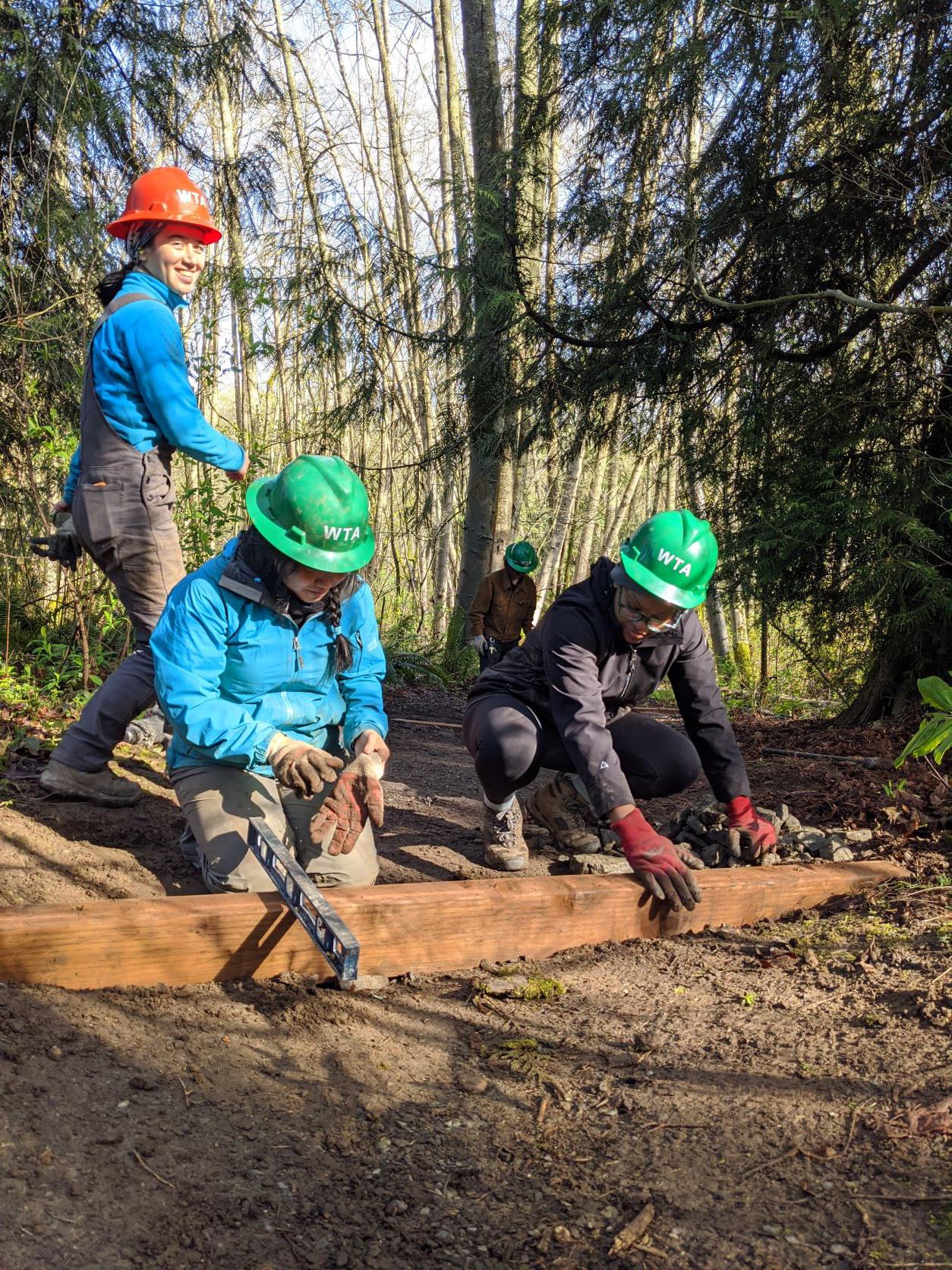 Tiffany working with the ELP cohort at Discovery Park on putting water bars into the trail and leveling them with a spirit level. Photo by Zachary Toliver.