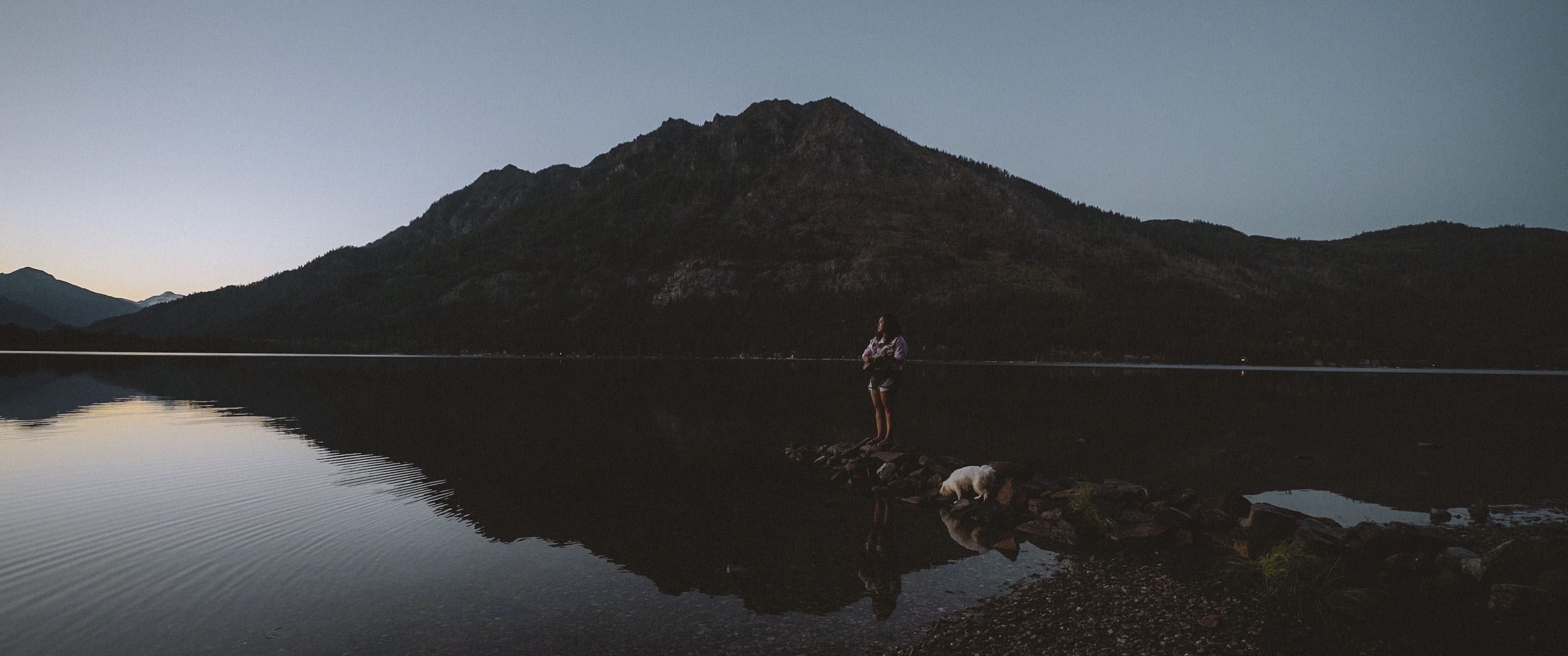 Nikki in a still from the film. Image by Sanjana Sekhar. Nikki stands on a rock over a lake near sunset.