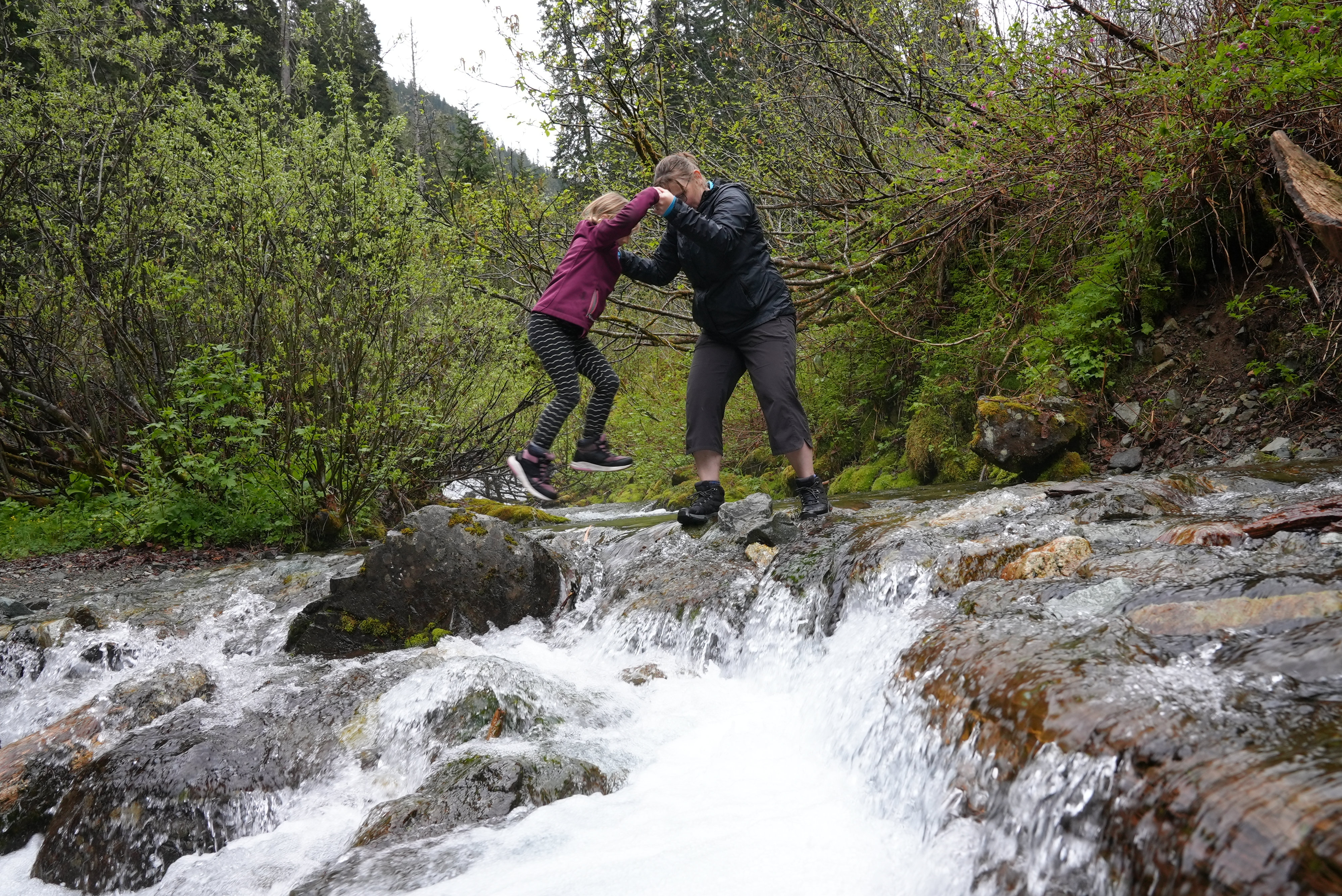 Mother helps child cross river.