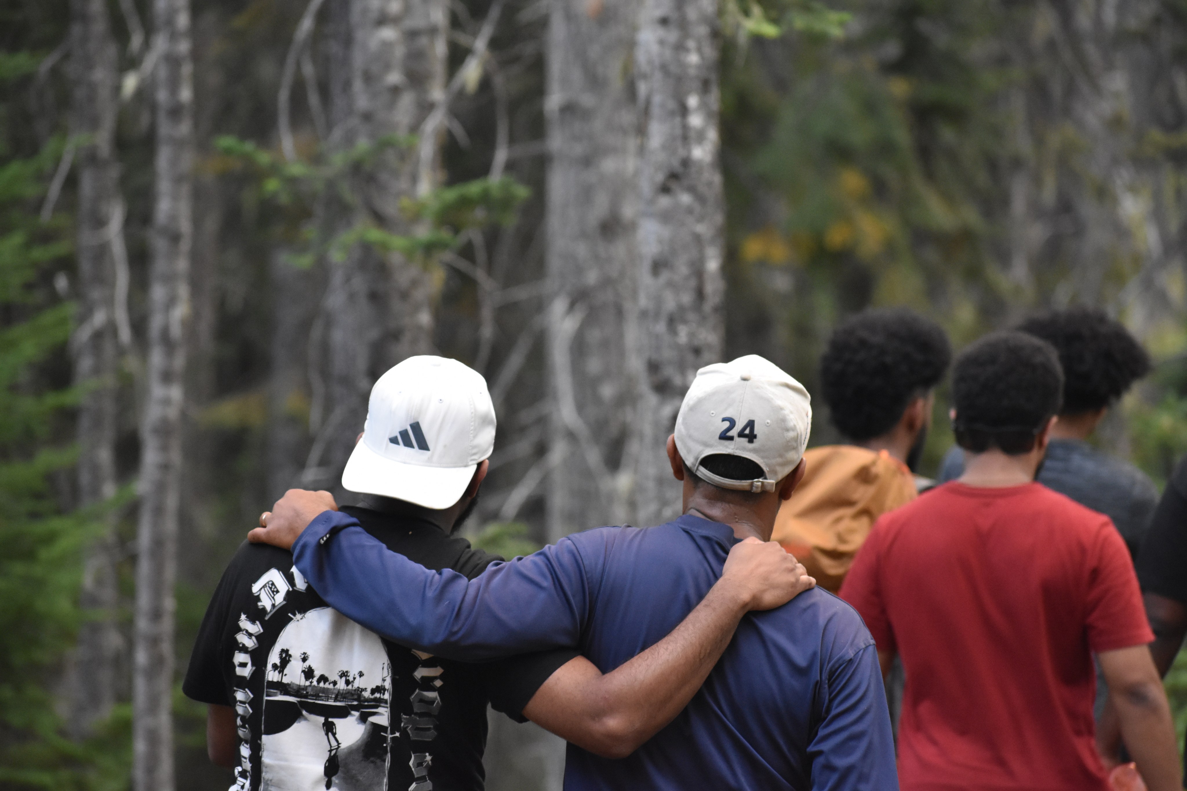 Group hiking on trail. Close up of two people embracing in a side hug.