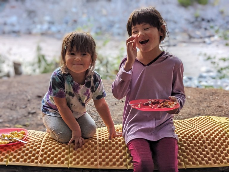 Nisqually River. Photo by DavidMcGovern Two young sisters sit together near a river, enjoying a picnic.